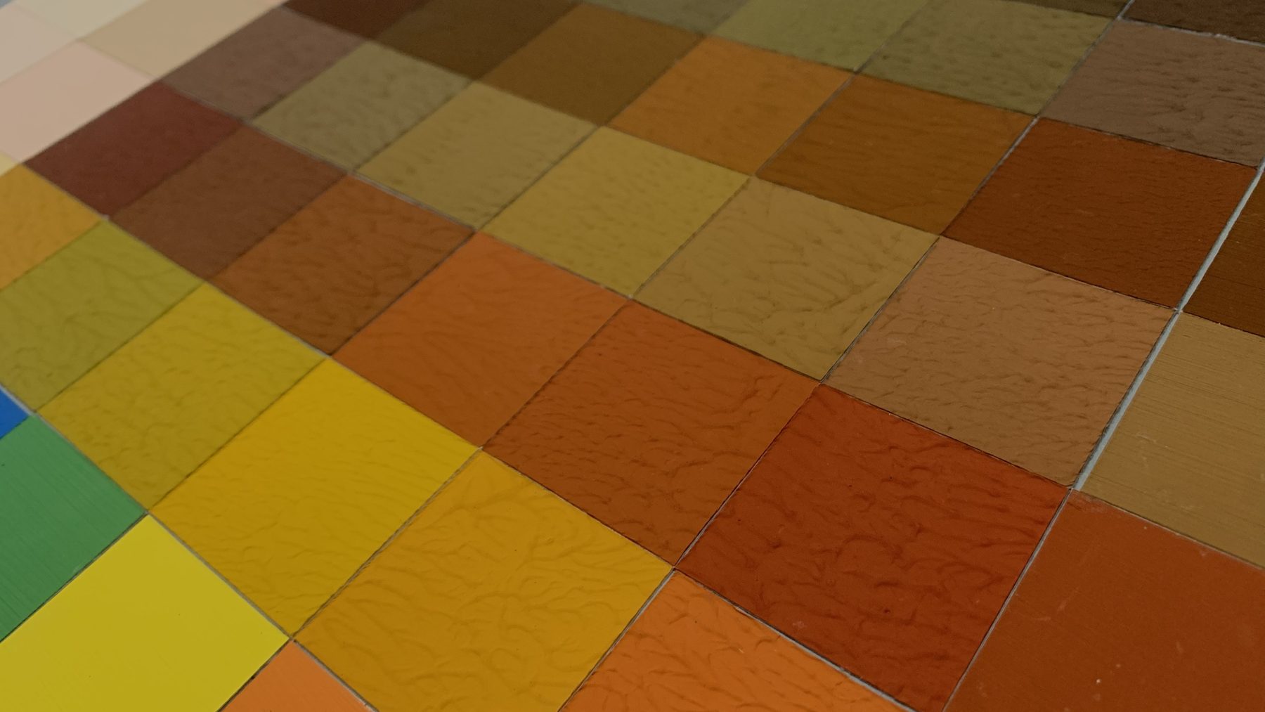 Carrés de nuancier en lumière rasante, laissant voir la texture de l'enduit